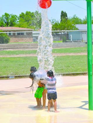 Jared Briones, Jimena Torres and Jareni Torres get doused while playing at the Splash Pad next to Towle Park Pool Friday afternoon. The pool will open for the summer season Tuesday.